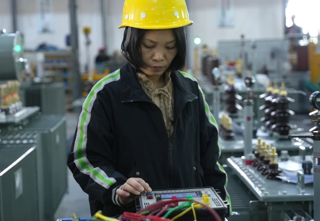Technician operating a CT analyzer for built-in current transformer ratio and polarity check on a distribution transformer