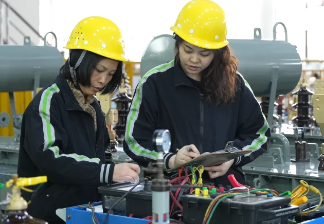 Two technicians measuring transformer winding resistance using a winding resistance meter during routine testing